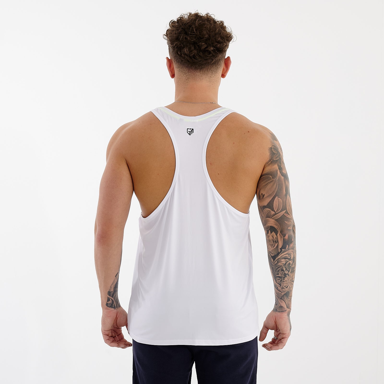Back view of a man wearing a white essential tank top