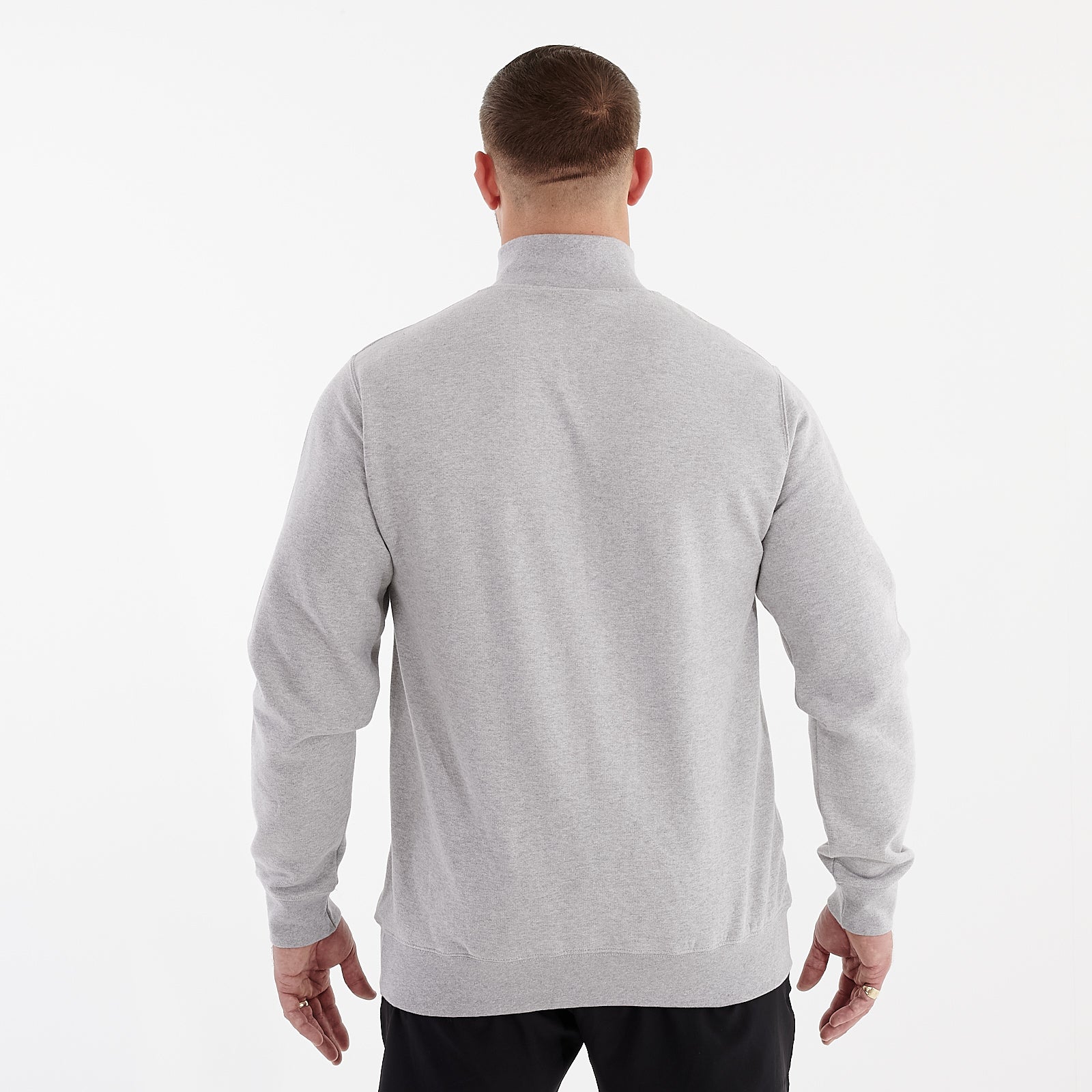 Back view of a man wearing a grey 1/4 zip sweatshirt