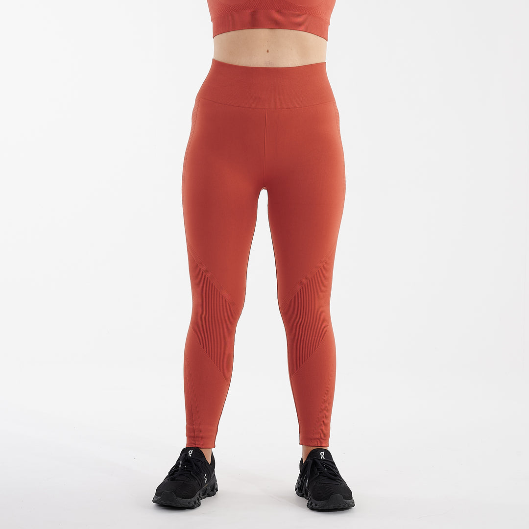 Front view of a woman wearing orange sculpt fit multi sport leggings