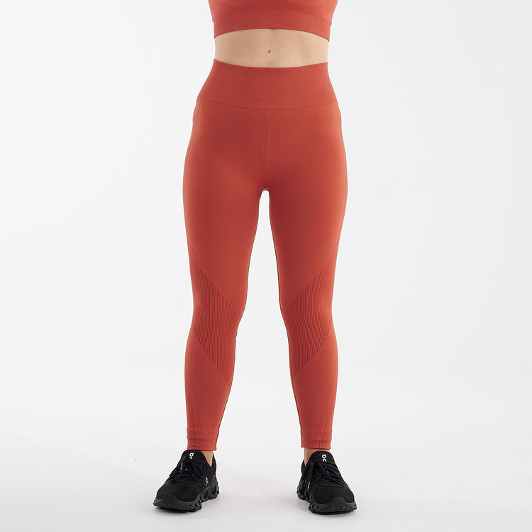 Front view of a woman wearing orange sculpt fit multi sport leggings