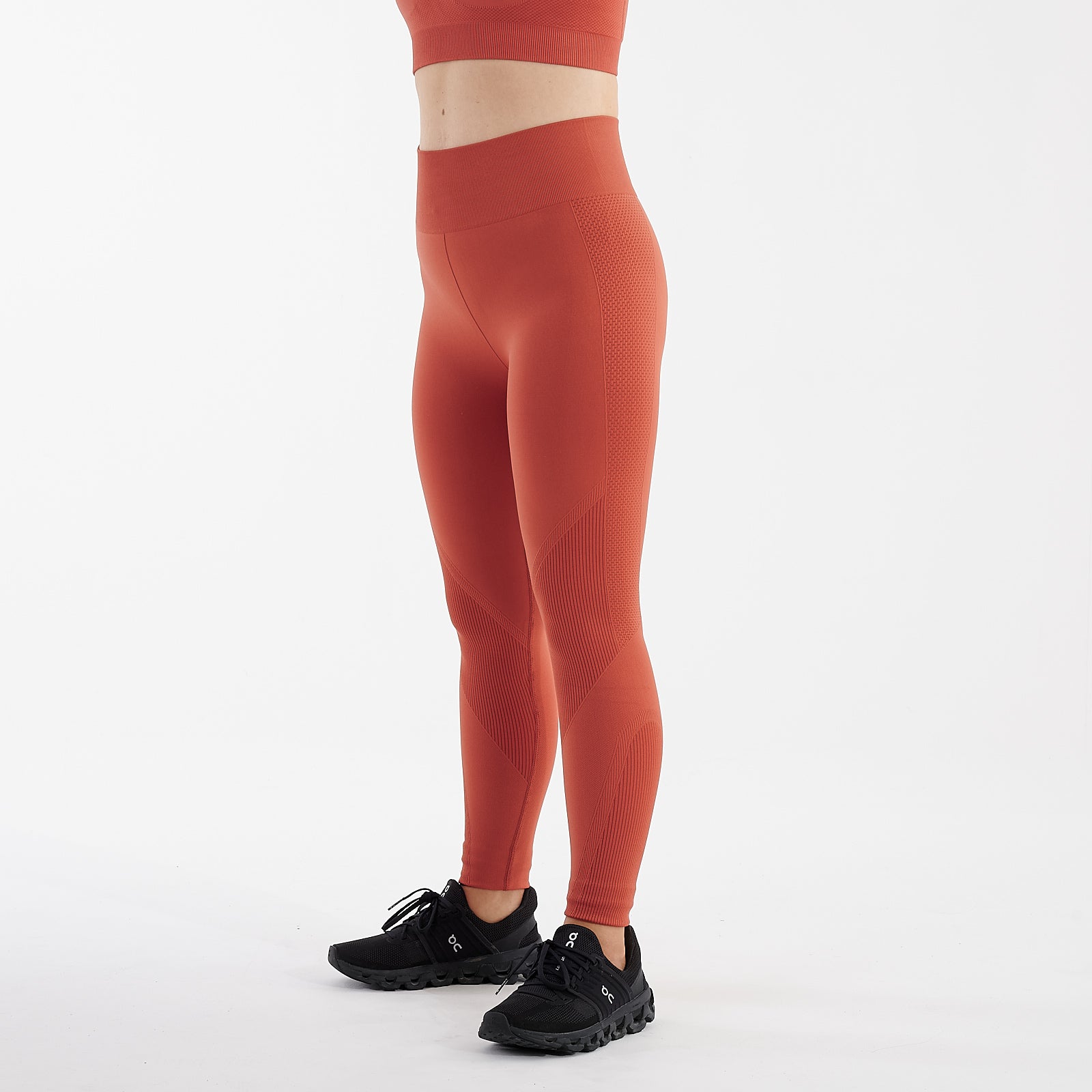 Side view of a woman wearing orange sculpt fit multi sport leggings