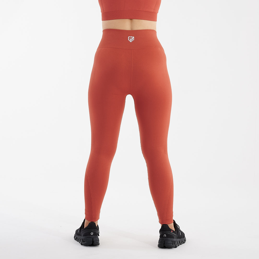 Back view of a woman wearing orange sculpt fit multi sport leggings