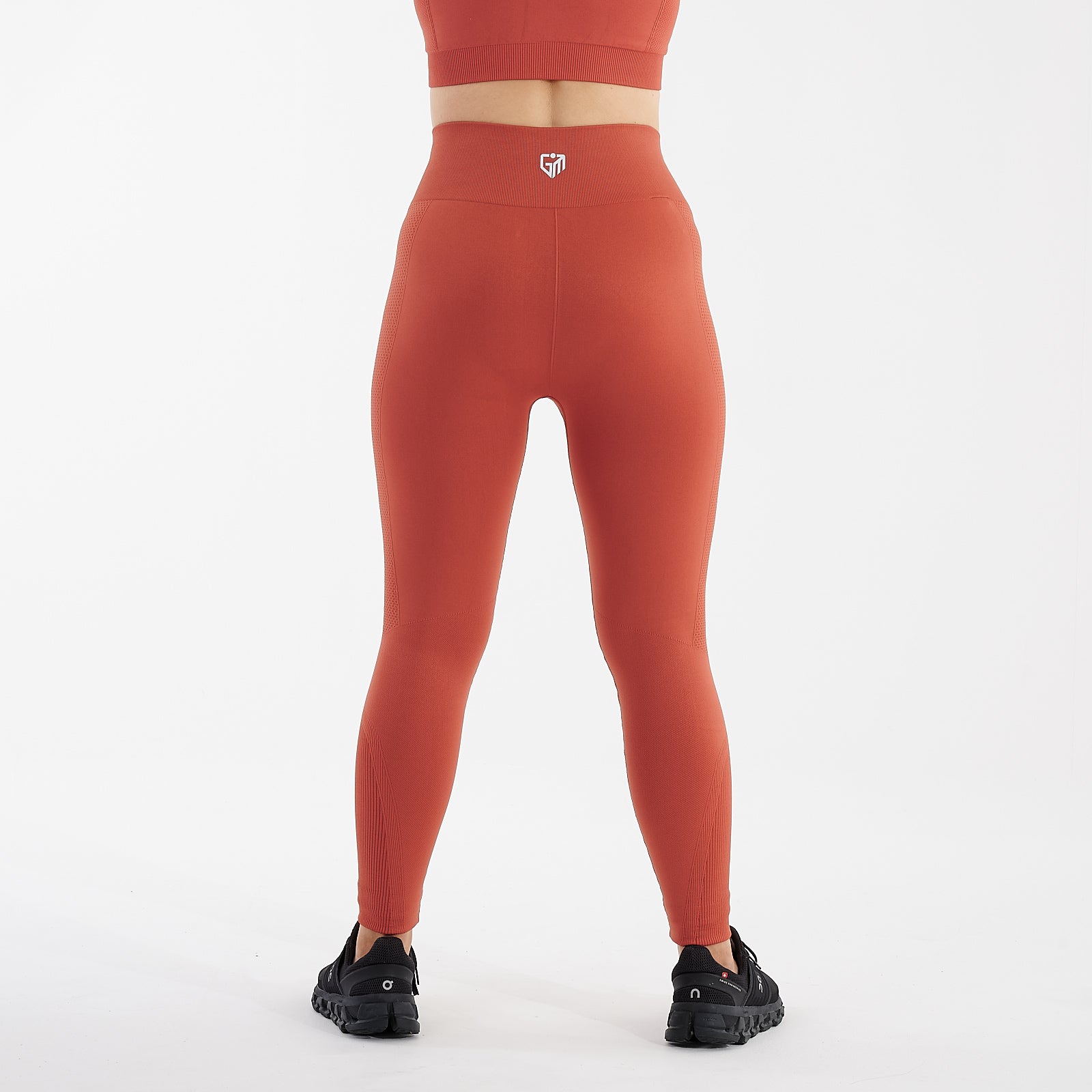 Back view of a woman wearing orange sculpt fit multi sport leggings