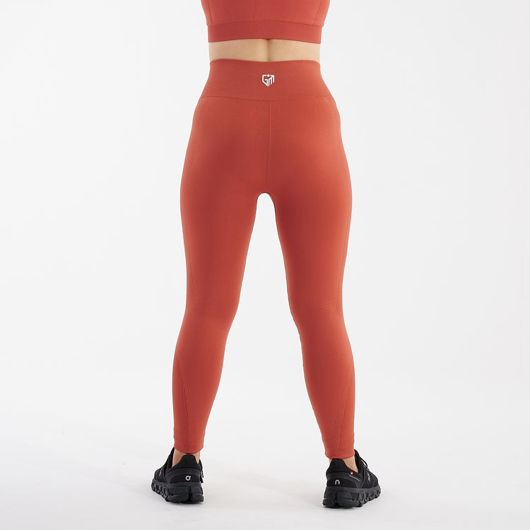 Back view of a woman wearing orange sculpt fit multi sport leggings