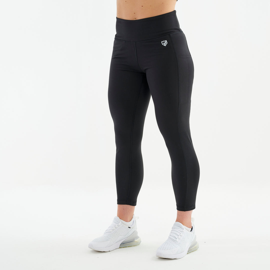 Side view of a woman wearing black 7/8 recycled performance leggings