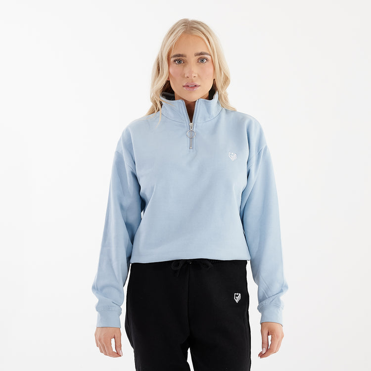 Front view of a woman wearing a sky blue cropped 1/4 zip sweatshirt