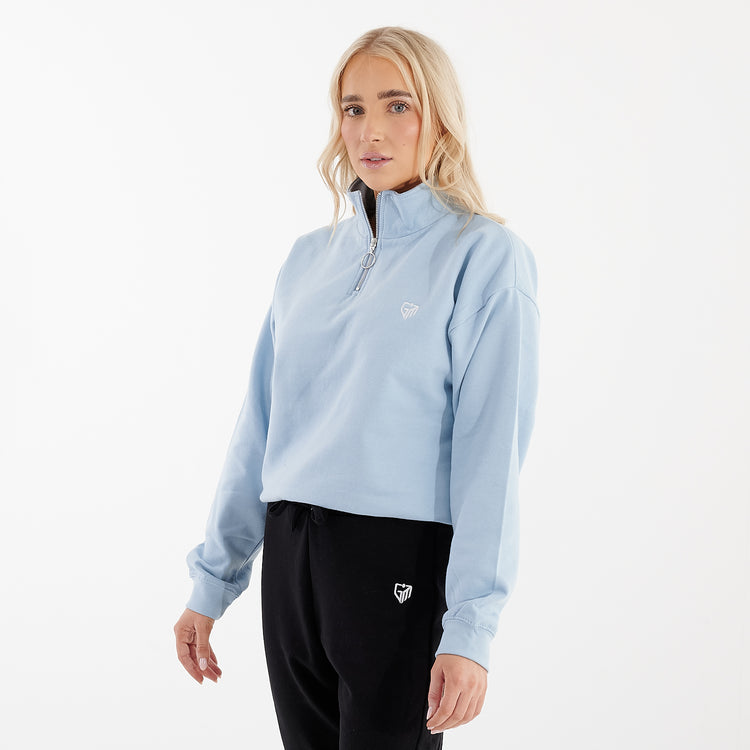 Side view of a woman wearing a sky blue cropped 1/4 zip sweatshirt
