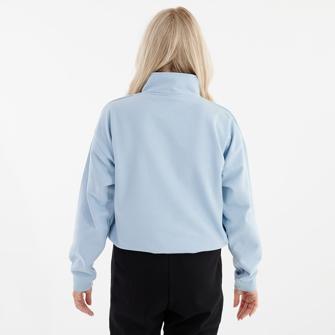 Back view of a woman wearing a sky blue cropped 1/4 zip sweatshirt