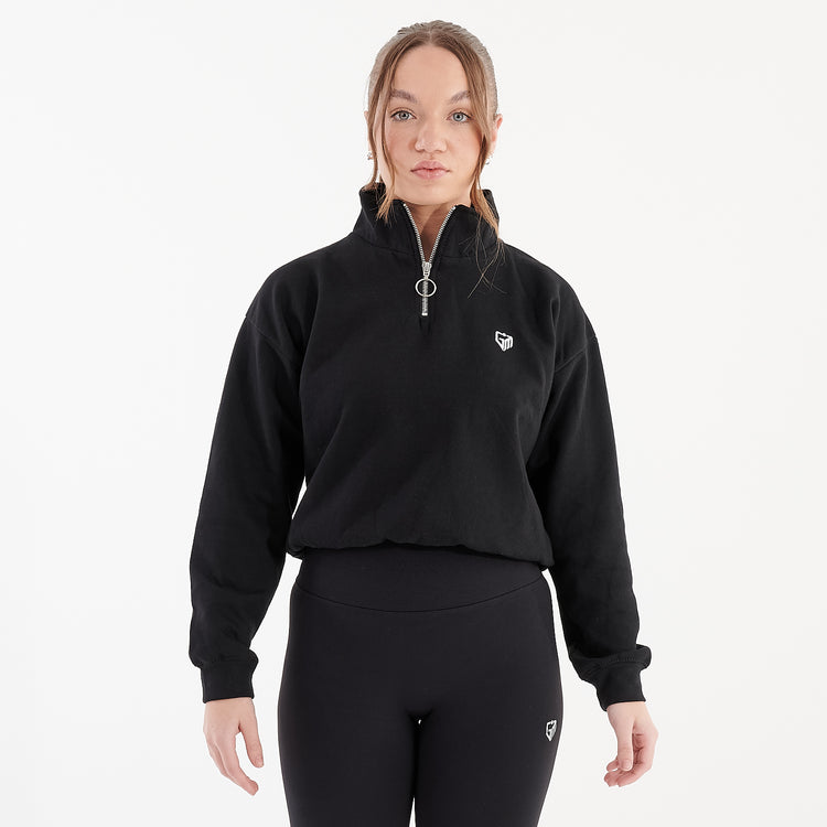 Front view of a woman wearing a black cropped 1/4 zip sweatshirt