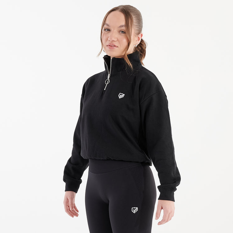 Side view of a woman wearing a black cropped 1/4 zip sweatshirt