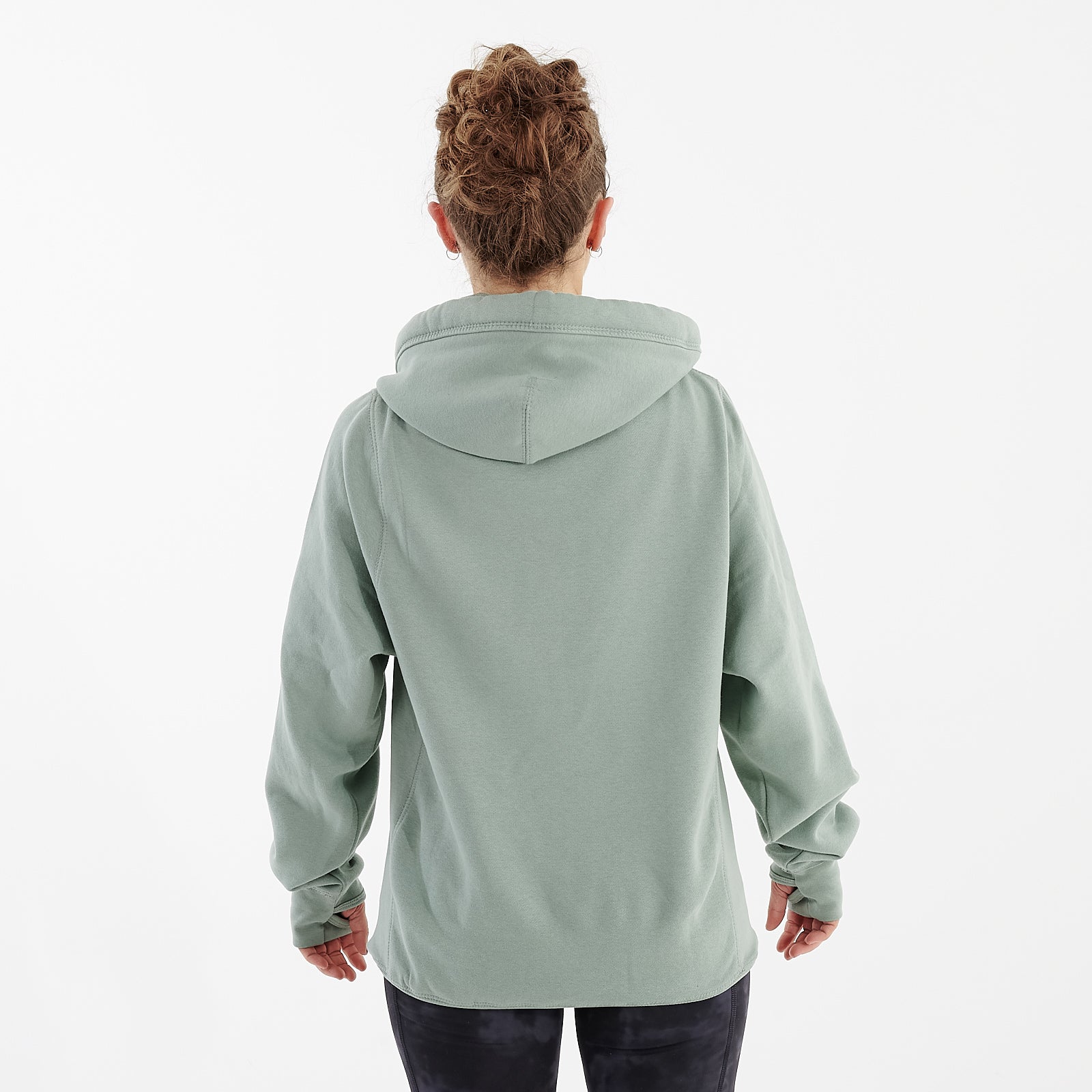 Back view of a woman wearing a dusty green heavyweight hoodie