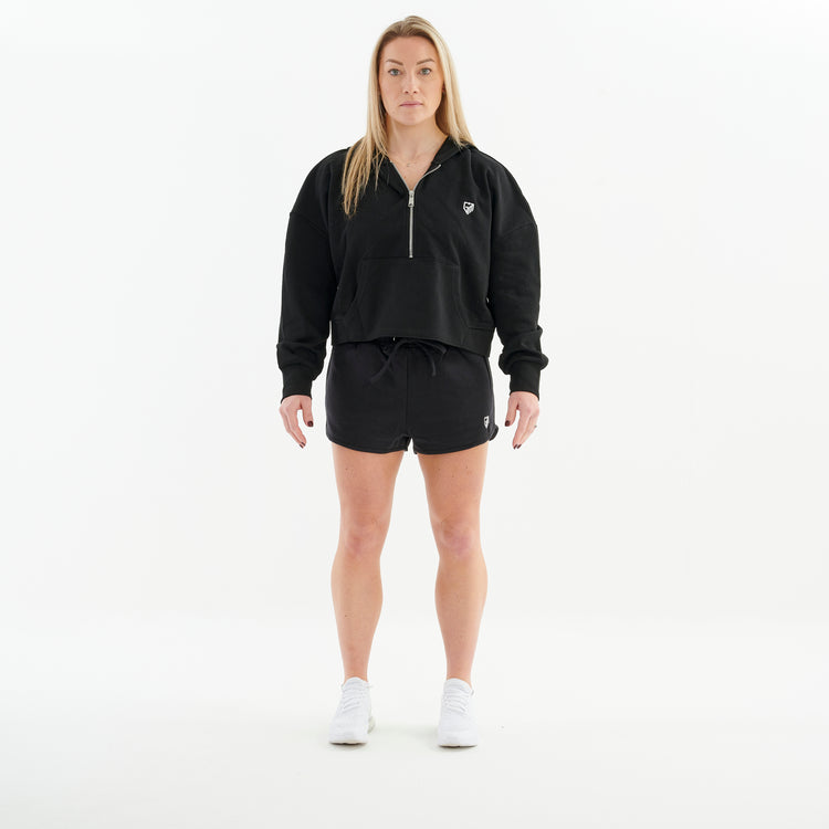 Front view of a woman wearing a half zip cropped hoodie in black