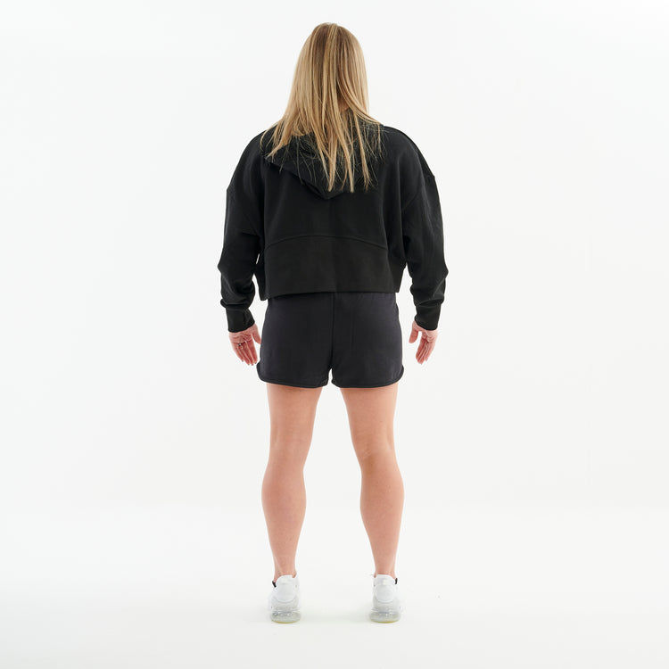 Back view of a woman wearing a half zip cropped hoodie in black