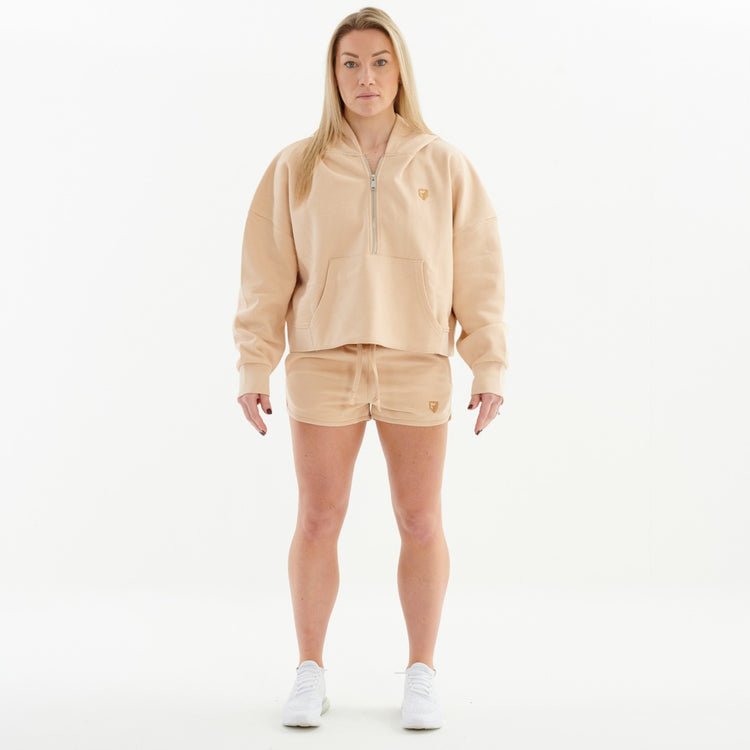 Front view of a woman wearing a nude 1/2 zip cropped hoodie