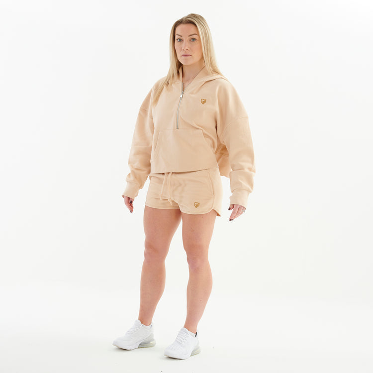 Side view of a woman wearing a nude 1/2 zip cropped hoodie