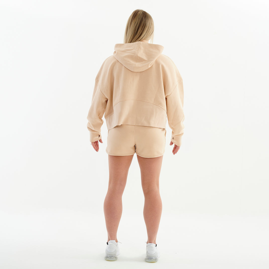 Back view of a woman wearing a nude 1/2 zip cropped hoodie