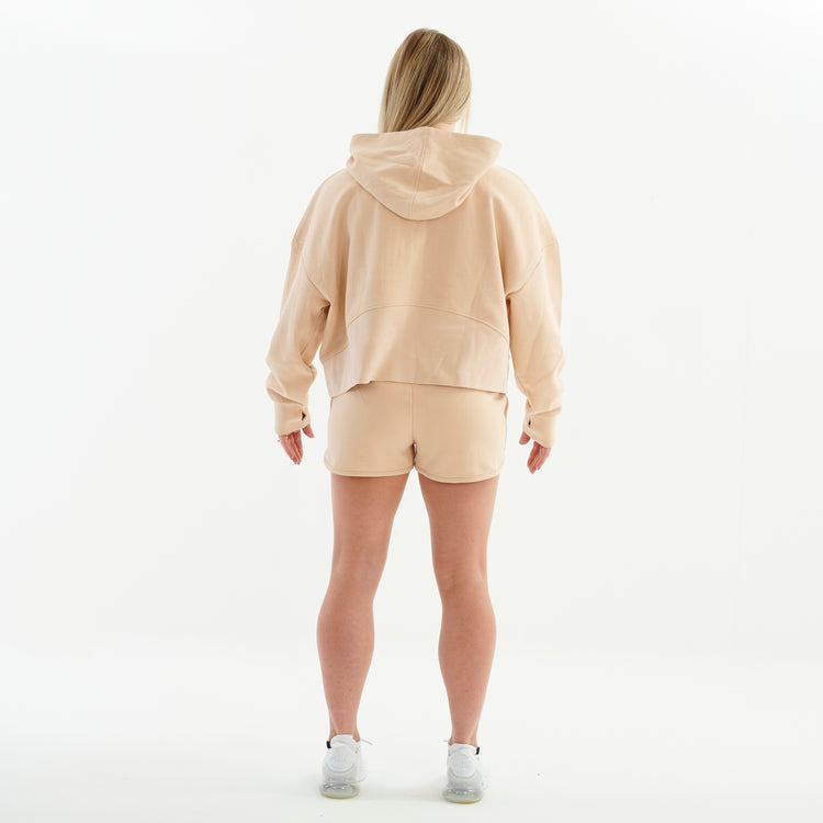 Back view of a woman wearing a nude 1/2 zip cropped hoodie