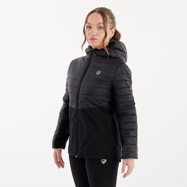 Side view of a woman wearing a black insulated hybrid jacket