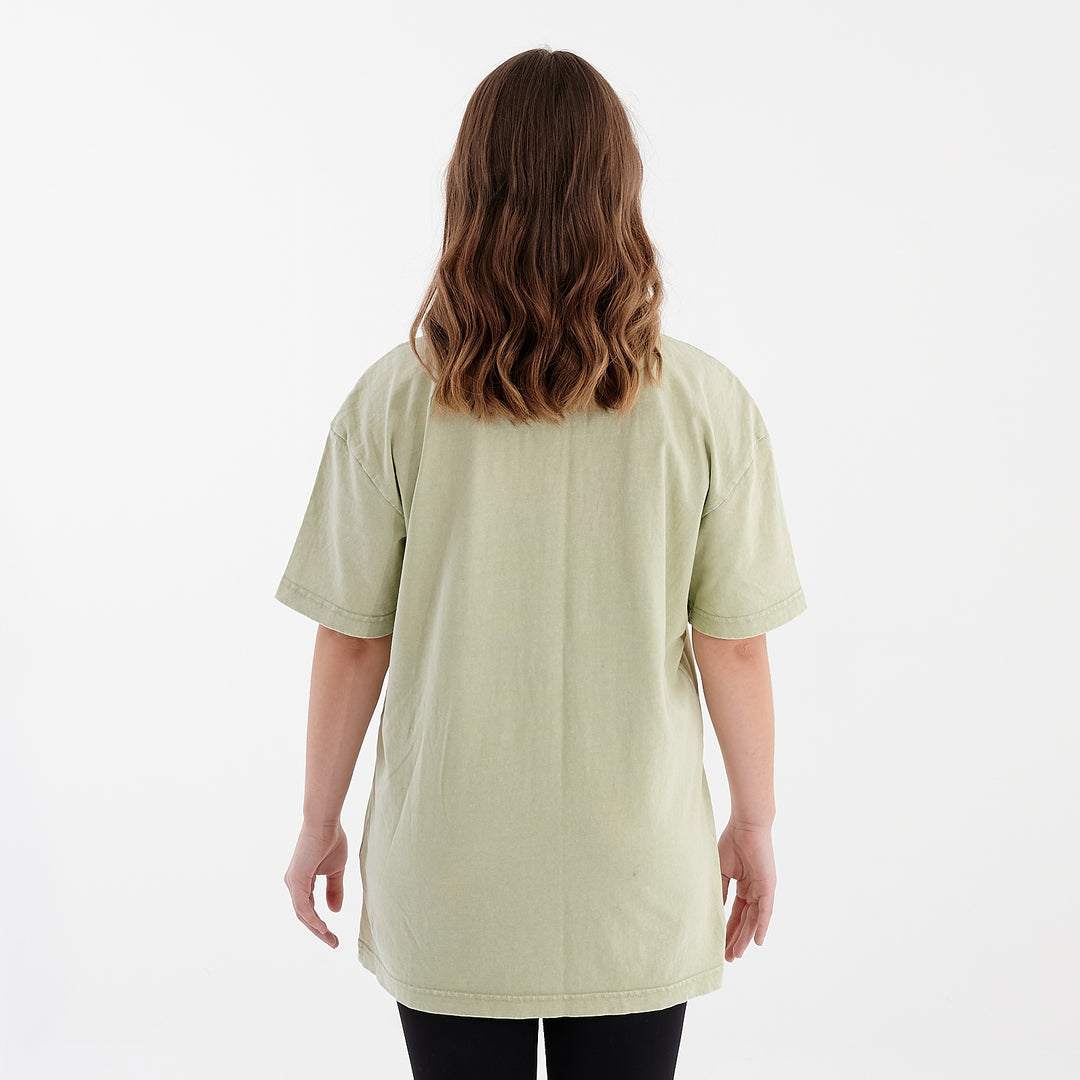 Back view of a woman wearing an oversized acid wash tee in soft salvia