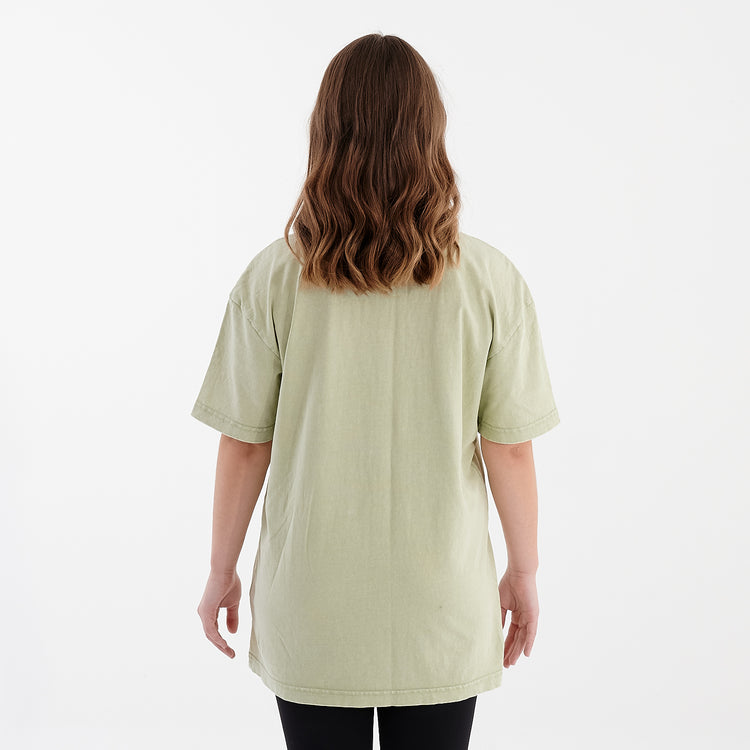 Back view of a woman wearing an oversized acid wash tee in soft salvia