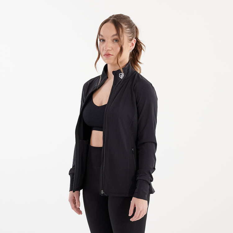 Side view of a woman wearing a black recycled fitness jacket unzipped