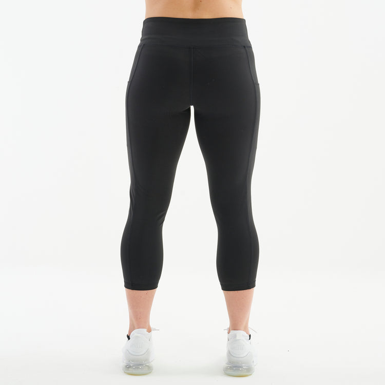 Back view of a woman wearing recycled 3/4 length performance leggings