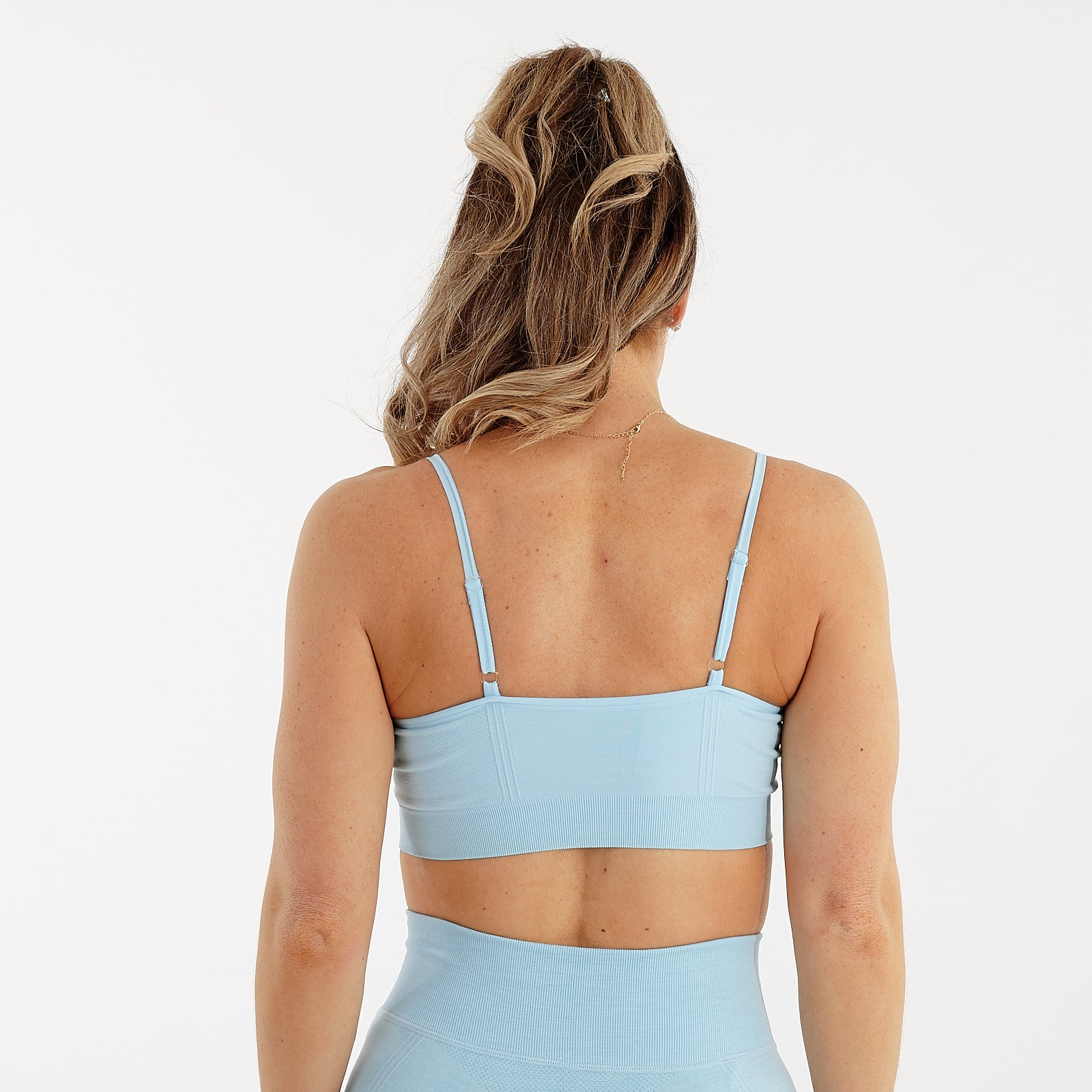 Back view of a woman wearing a sky blue seamless flex bra